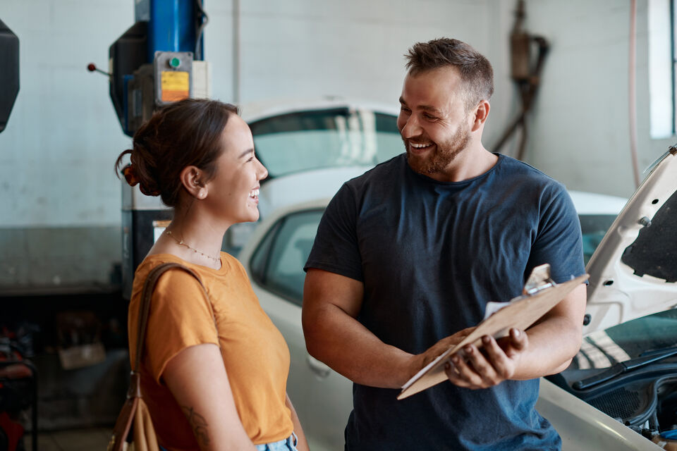 Mechanic showing a customer a clipboard while discussing her car
