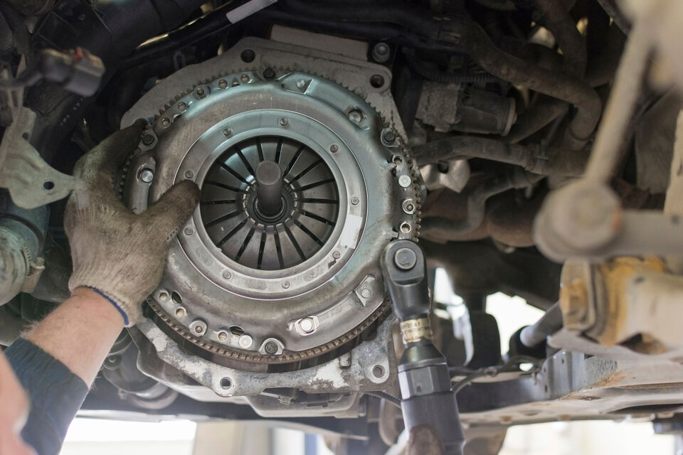 Mechanic's gloved hand holding a clutch assembly during a gearbox repair