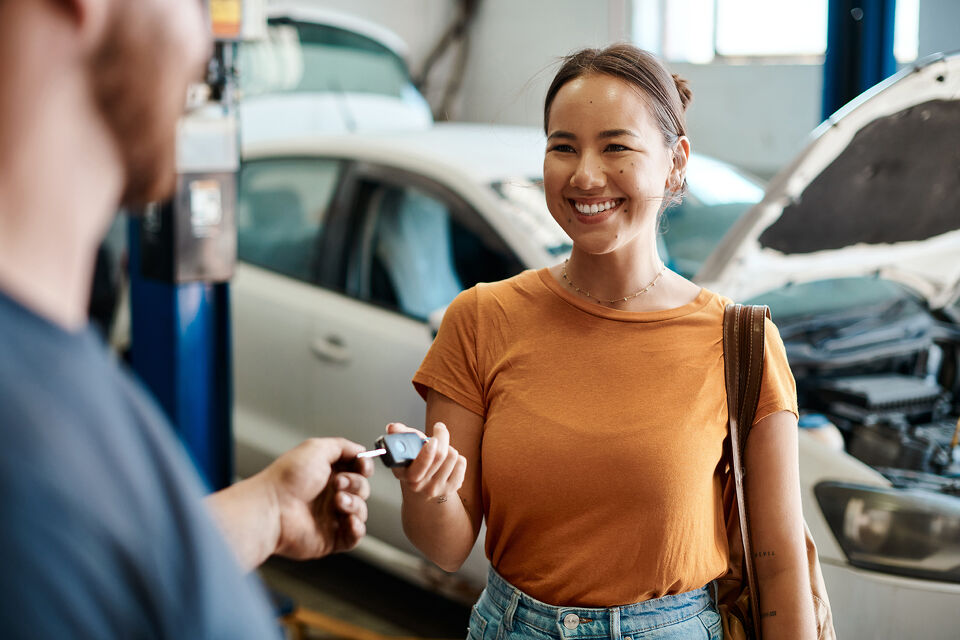 Mechanic handing car keys back to a smiling customer in the workshop