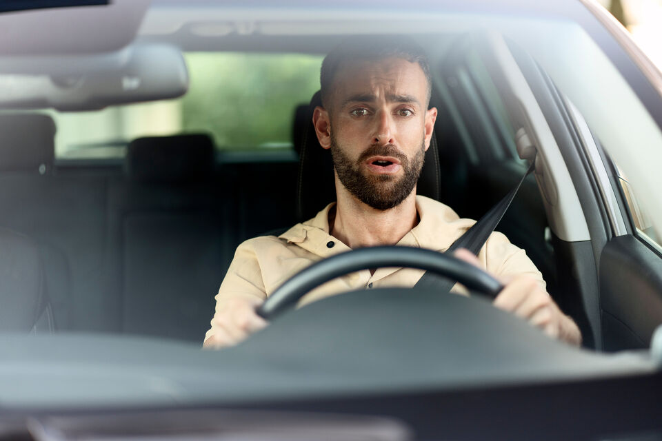 Concerned man gripping the steering wheel while driving