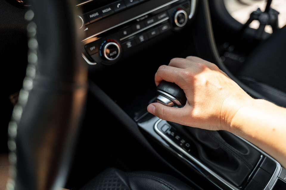 Hand operating a gear selector inside a car with automatic climate controls
