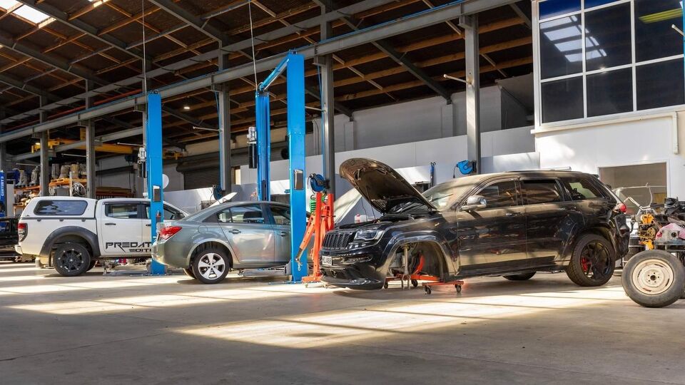 Vehicles with bonnets up inside the Marshall Automotive workshop