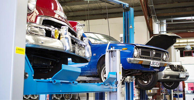 Classic cars raised on hoists inside the Marshall Automotive workshop